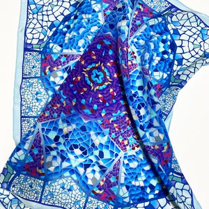 May include: A blue and purple silk scarf with a mosaic pattern. The scarf is folded and draped over a white surface.