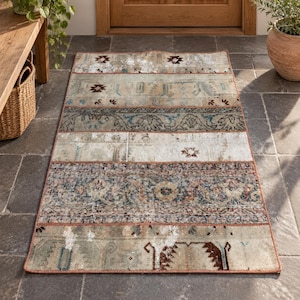 May include: A rectangular area rug featuring a patchwork design composed of horizontal bands with varying patterns in muted tones of beige, gray, blue, and rust. The rug has a finished edge and displays a distressed, weathered appearance throughout.