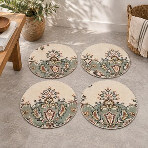 May include: Four circular rugs featuring a cream-colored background with a decorative border in sage green, brown, and dark red. Each rug displays a symmetrical floral pattern with intricate botanical motifs centered on the lower half of the circle.