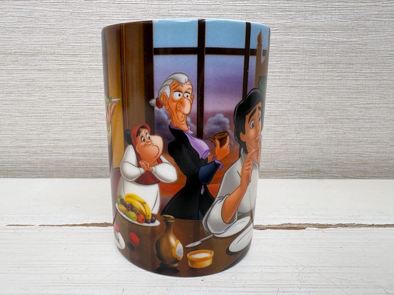 May include: A cylindrical ceramic mug featuring a colorful illustration of animated characters. The design includes a dining scene with figures in a room with a window. The mug has a brown background with a blue sky.