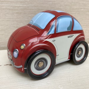 Puede incluir: Un coche de juguete rojo y blanco con ruedas negras. El coche tiene un parabrisas azul y una franja blanca alrededor del medio.