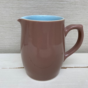 May include: A brown ceramic jug with a light blue interior and a rounded handle.