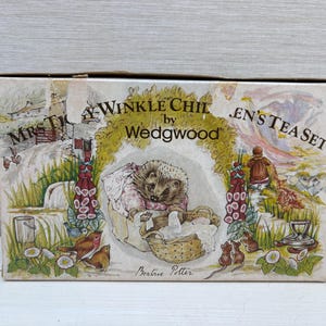 Könnte beinhalten: Ein rechteckiger Karton für ein Mrs. Tiggy-Winkle Kinder-Teeservice von Wedgwood. Die Schachtel zeigt eine farbenfrohe Illustration eines Igels in einem Korb, umgeben von Blumen, Vögeln und Mäusen, mit dem aufgedruckten Text Beatrix Potter.