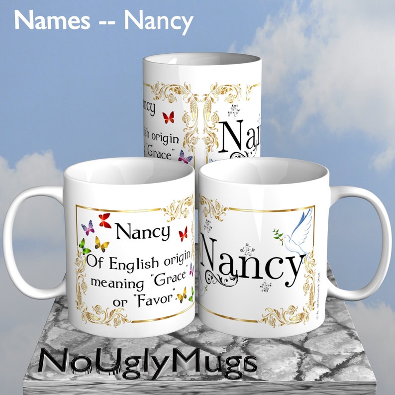 May include: Three white ceramic mugs with gold trim and a decorative design featuring butterflies and the name "Nancy". The mugs have the text "Of English origin meaning "Grace" or "Favor" printed on them. The mugs are on a textured surface with a blue sky background.