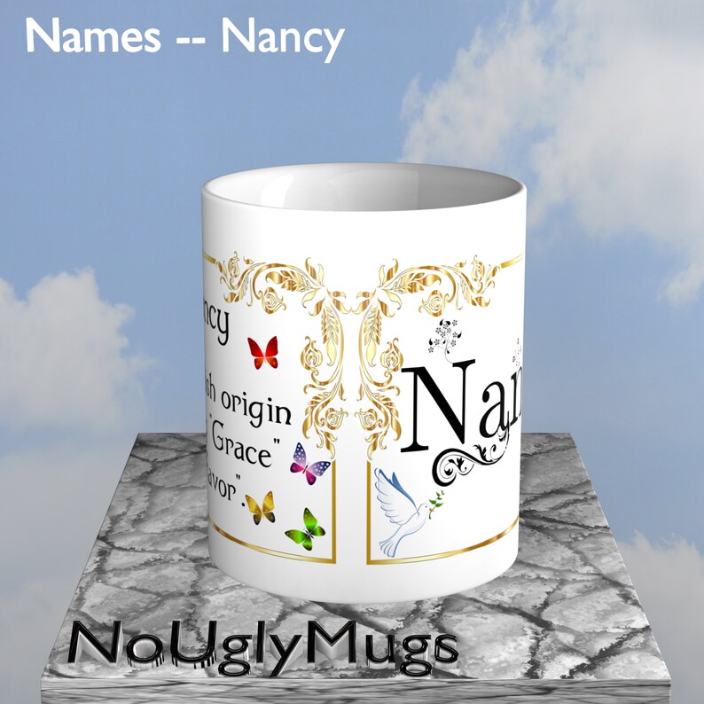 May include: White ceramic coffee mug with a gold design and the name "Nancy" in gold lettering. The mug has a quote about the name's origin and features colorful butterflies and a white dove with an olive branch.