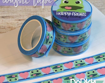 May include: Four rolls of blue and pink washi tape with a frog design and the text "Happy Frogs Dorky doodles". The tape is on a white surface with the text "Dorky prints n' doodles www.dorkydoodles.com" at the bottom.