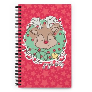 May include: A red spiral notebook with a cute cartoon reindeer wearing a green wreath with red berries and the text "jingle bells". The background is a red pattern of white stars.
