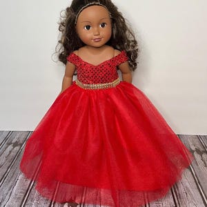 May include: A red tulle dress with a sequined bodice and a gold belt. The dress is designed for a doll.