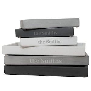 Peut inclure: Une pile de quatre plateaux en b&eacute;ton gris avec les mots "the Smiths" grav&eacute;s sur chaque plateau.