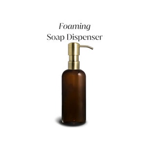 May include: A brown glass foaming soap dispenser with a gold pump top. The dispenser is labeled "Foaming Soap Dispenser".