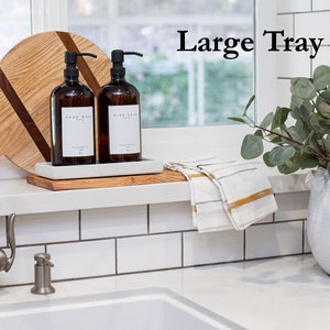 Peut inclure: Un plateau en bois avec deux bouteilles en verre ambr&eacute; avec des pompes, l'une &eacute;tiquet&eacute;e "Lavage des mains" et l'autre "Savon &agrave; vaisselle". Le plateau est pos&eacute; sur un comptoir blanc avec un dosseret en carrelage blanc. Un robinet argent&eacute; est visible au premier plan. Le texte "Grand plateau" est visible en arri&egrave;re-plan.