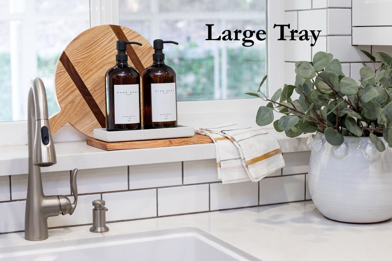 Peut inclure: Un plateau en bois avec deux bouteilles en verre ambr&eacute; avec des pompes, l'une &eacute;tiquet&eacute;e "Lavage des mains" et l'autre "Savon &agrave; vaisselle". Le plateau est pos&eacute; sur un comptoir blanc avec un dosseret en carrelage blanc. Un robinet argent&eacute; est visible au premier plan. Le texte "Grand plateau" est visible en arri&egrave;re-plan.
