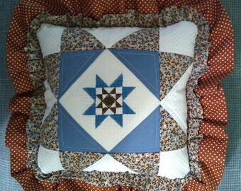 Patchwork throw pillow with cross stitch motif in center.   Pillow is 10" square, with ruffle measures 14" square.