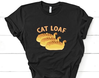 Op de afbeelding: Zwart T-shirt met de tekst "Cat Loaf" en een afbeelding van drie katten in de vorm van brood.