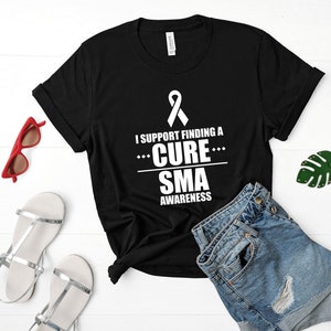 May include: Black t-shirt with a white ribbon and the text "I support finding a cure... SMA awareness".
