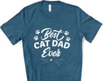 May include: A teal-colored t-shirt with the text "Best Cat Dad Ever" in white, along with paw prints and a cat whisker design. The shirt is made of a soft material.