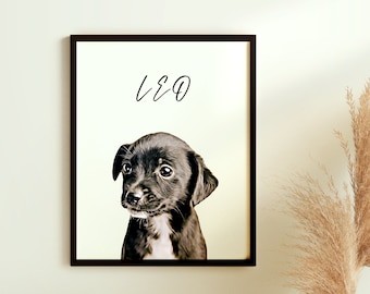 May include: A framed print featuring a black and white puppy portrait. The puppy has a sweet expression and is centered in the frame. The word "LEO" is written above the puppy in a handwritten font. The frame is dark brown.