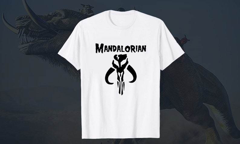 Puede incluir: Camiseta blanca con un s&iacute;mbolo mandaloriano negro y el texto "MANDALORIAN" impreso en la parte delantera.
