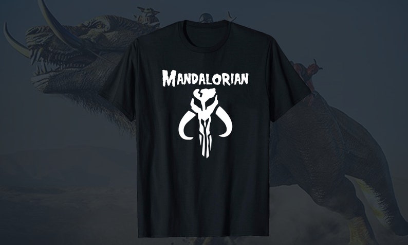 Puede incluir: Camiseta negra con un s&iacute;mbolo mandaloriano blanco y el texto "MANDALORIAN" impreso en la parte delantera.