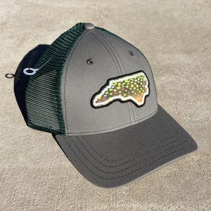 Może przedstawiać: Szara i zielona czapka trucker z naszywką stanu Karolina Północna, zaprojektowana tak, aby przypominała pstrąga.