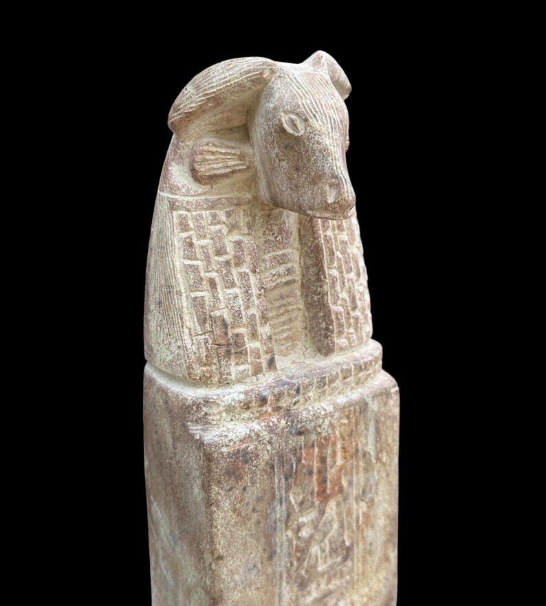 May include: A carved stone statue of an Egyptian god with a bull's head. The statue is weathered and has a light brown colour.