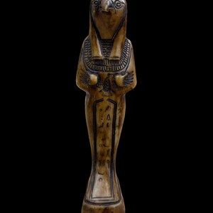 May include: A carved wooden figurine of an Egyptian god with a falcon head, wearing a traditional headdress and holding a staff. The figurine is decorated with hieroglyphs.