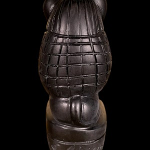 May include: Black ceramic figurine of a bear wearing a plaid coat and hat. The bear is sitting on a base with the word "Griffin" inscribed on it.