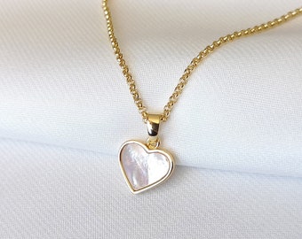 Può includere: Una collana con catena dorata e un ciondolo a forma di cuore bianco.