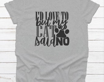 May include: A grey t-shirt featuring the black text "I'D LOVE TO but my CAT said NO" and a cat paw print. The shirt has a crew neck and short sleeves. The fabric appears soft.