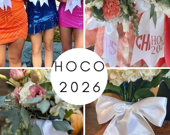 May include: White satin ribbons attached to floral bouquets, featuring custom glitter monograms and the text HOCO 2024. The ribbons have a notched end and are tied around the stems of various flower arrangements in different colors.