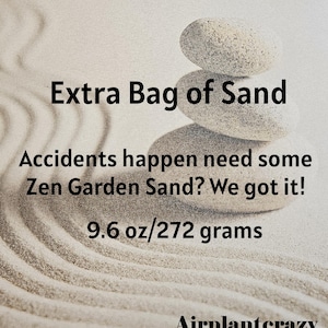 May include: Image of a zen garden theme. A stack of three smooth, gray stones is centered above a sand design. Text reads: "Extra Bag of Sand. Accidents happen need some Zen Garden Sand? We got it! 9.6 oz/272 grams."
