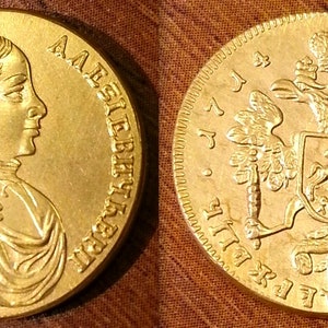 Puede incluir: Una moneda de oro con el retrato de una mujer en un lado y un águila bicéfala con un escudo en el otro. El texto en la moneda dice "IMPERATRIX  ALL  RUSSIAE" y "ЕКАТЕРИНА II  ВСЕРОССИЙСКАЯ  ИМПЕРАТРИЦА".