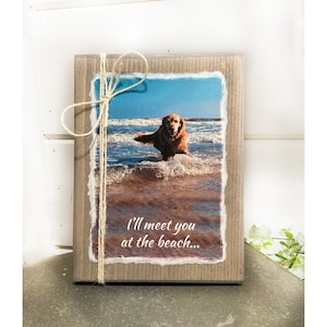 May include: A wooden sign with a photo of a golden retriever dog running in the ocean. The sign has a rustic look and says "I'll meet you at the beach..."