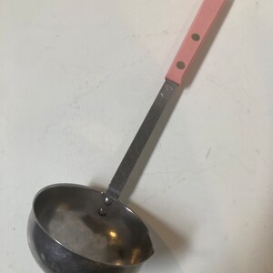 May include: A stainless steel ladle with a pink handle. The handle has two silver dots on it.