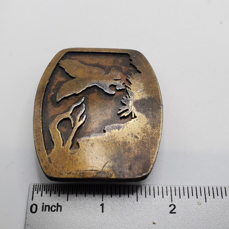 Op de afbeelding: Een messing gesp met een ontwerp van een vliegende vogel. De gesp is ongeveer 2,5 cm breed.