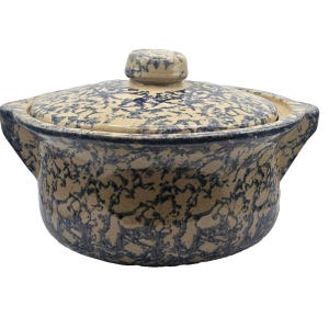 May include: A stoneware casserole dish with a lid. The dish is beige with a blue speckled pattern. It has two handles and a knob on the lid. The dish is designed for cooking and serving.