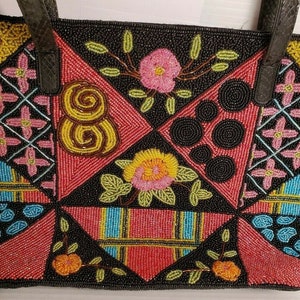 May include: A black tote bag with a patchwork design made of colorful beads. The bag features a variety of patterns, including flowers, swirls, and geometric shapes.