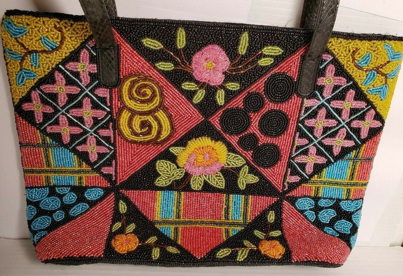 May include: A black tote bag with a patchwork design made of colorful beads. The bag features a variety of patterns, including flowers, swirls, and geometric shapes.