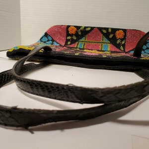 May include: A black beaded tote bag with a colorful geometric pattern and black leather straps. The bag has a zipper closure and is decorated with pink, yellow, blue, and green beads.