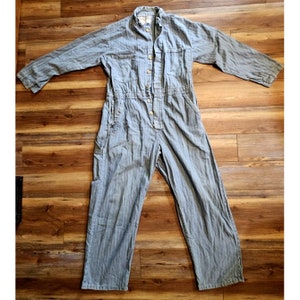 May include: A light blue denim jumpsuit with a button-up front and multiple pockets.