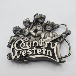 May include: Silver belt buckle featuring a group of four musicians playing instruments with the words "Country Western" in a stylized font.