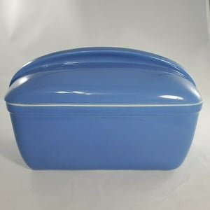 May include: A light blue ceramic bread box with a white rim and a curved lid.