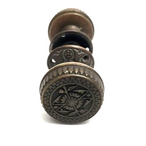 May include: Antique brass door knob with intricate floral design. The knob has a circular shape with a raised edge and a detailed pattern in the center.