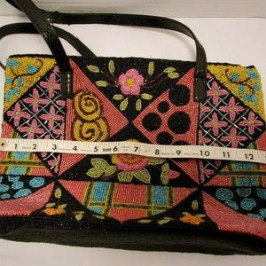 May include: A black beaded tote bag with a patchwork design featuring pink, yellow, blue, and green beads. The bag has a black leather strap and a black lining.