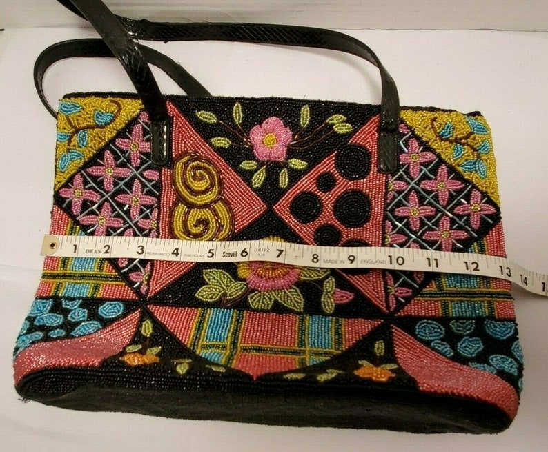 May include: A black beaded tote bag with a patchwork design featuring pink, yellow, blue, and green beads. The bag has a black leather strap and a black lining.