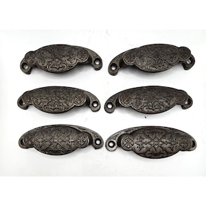 May include: Six antique cast iron drawer pulls with a floral design. The pulls are dark brown and have a slightly distressed finish.