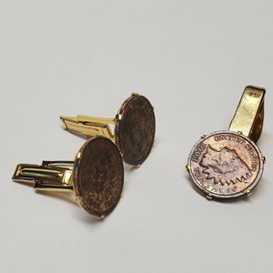 May include: A set of gold-toned cufflinks and a tie clip featuring vintage US coins. The coins are copper-colored and have a raised design of a Native American head.