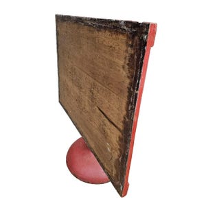 May include: A vintage wooden sign with a red border and a red, rounded base. The sign's wooden surface has a weathered appearance with visible wood grain and a dark border. The sign is angled, showcasing its side profile.