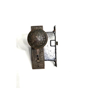 May include: Antique brass door knob and lock set with intricate floral and geometric designs. The knob features a circular design with a keyhole in the center.