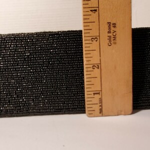 May include: A close-up of black beaded trim, measured with a ruler. The ruler shows measurements in inches and reads "Gold Bond #MCV 48".